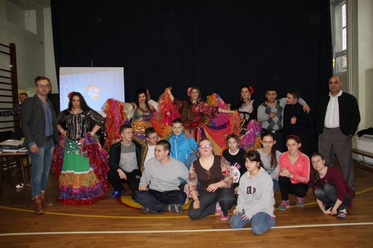 Grupa uczniów oraz Romów w szkolnej sali gimnastycznej