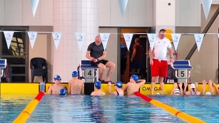 nauczyciel - trener dyktujący zadanie na rozgrzewkę zawodnikom w wodzie